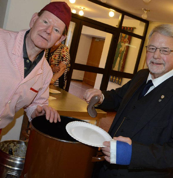 Metzgermeister Rolf Seidenberg bietet Peter Pott die Grtzwurst an.